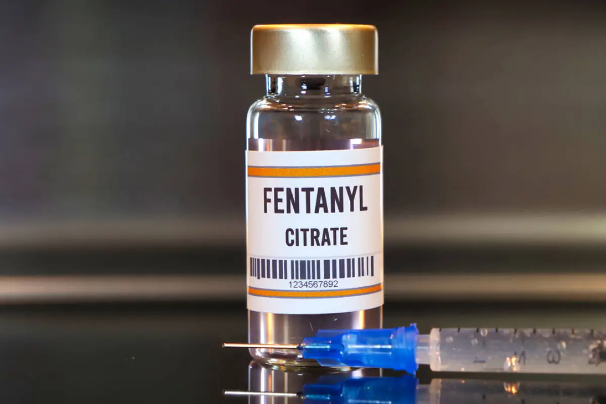 Fentanyl drug and syringe on black table with reflections and stainless background.,  
