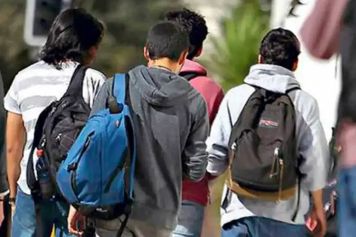 alumnos caminando con sus mochilas en la espalda