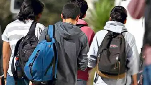 alumnos caminando con sus mochilas en la espalda