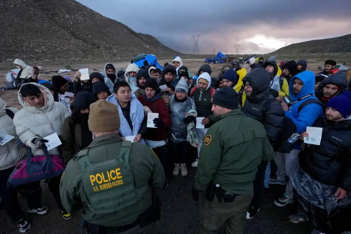 Migrantes en busca de asilo muestran sus papeles a dos agentes de la Patrulla Fronteriza, cerca de Jacumba (California). 02.02.2024, AP/Gregory Bull
